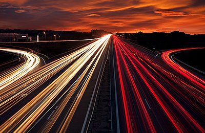Autobahn Lichtspuren bei dramatischem Sonnenuntergang Langzeitbelichtung einer Autobahn mit roten und weißen Lichtspuren bei Abendhimmel